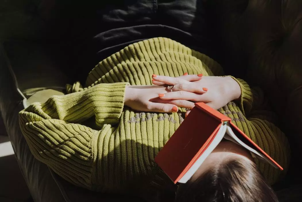A women with a book on her face sleeping.